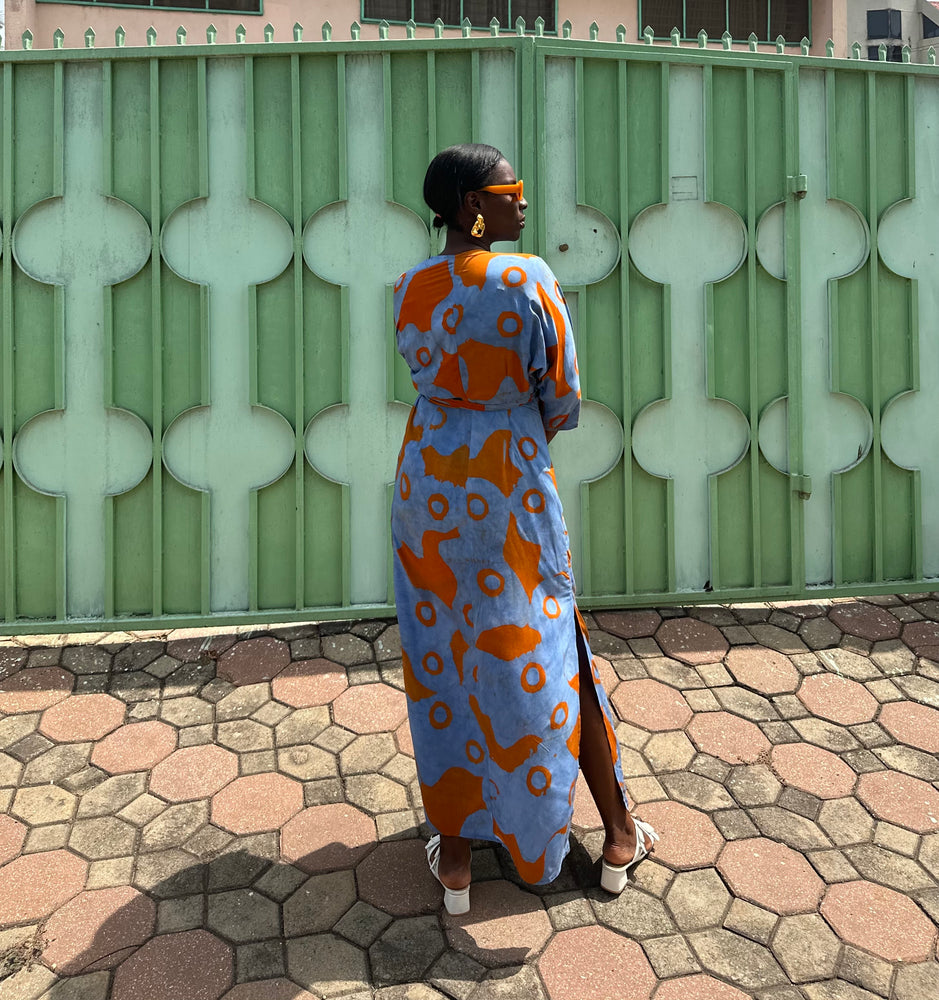 Back view of a woman in the rayon hand-batiked wrap dress with batwing sleeves, deep V neckline, soft pleats, and side slits.