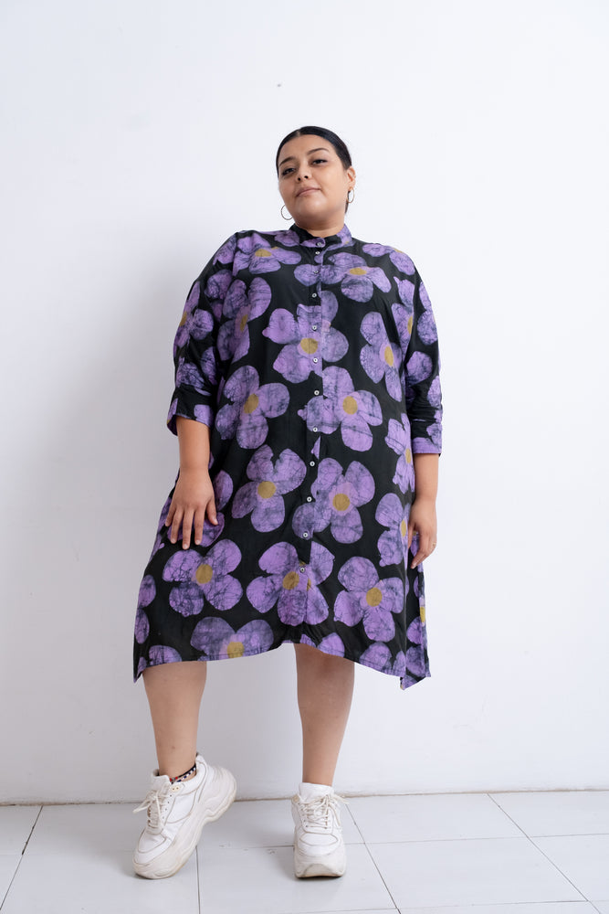 Long-sleeved Para Dress with large purple floral print and white sneakers, against a white wall.