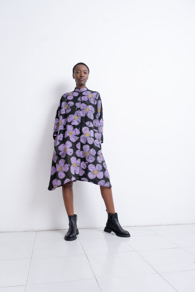 Long-sleeved knee-length Para Dress with purple floral pattern and black boots against a white wall.