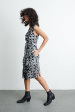Abstract Duplo Dress in 2 Party System print, paired with black ankle boots, model in mid-step against a white wall.