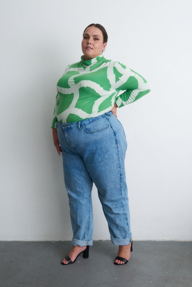 Profile view of Osei-Duro Stricta Turtleneck in Mangrove print, paired with high-waisted jeans and black heels.