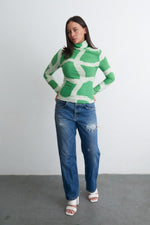 Osei-Duro Stricta Turtleneck in Mangrove print, styled with blue jeans, model stands poised against a plain backdrop.