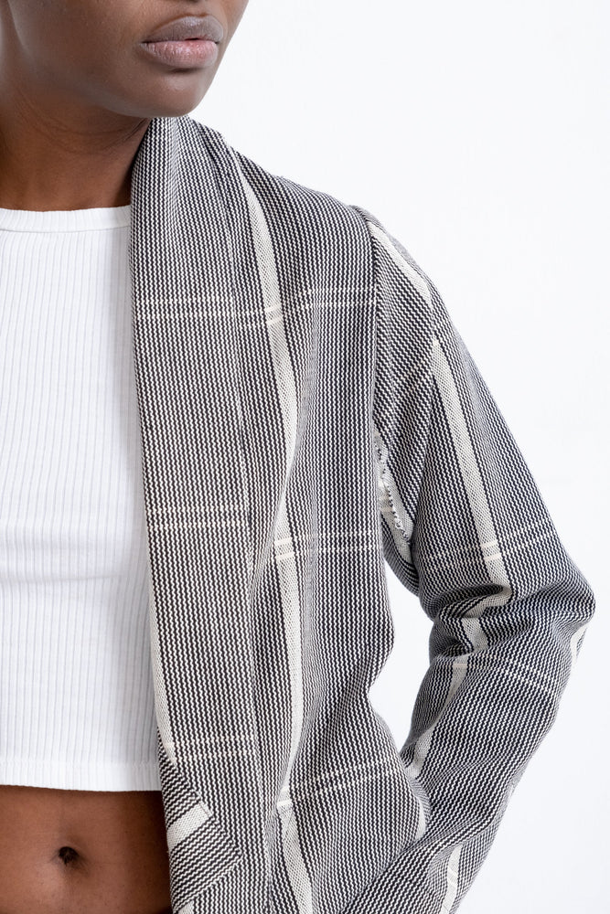 A stylish woman rocking a gray and white striped jacket, the Handwoven cotton Abiba Jacket in Guinea Fowl.