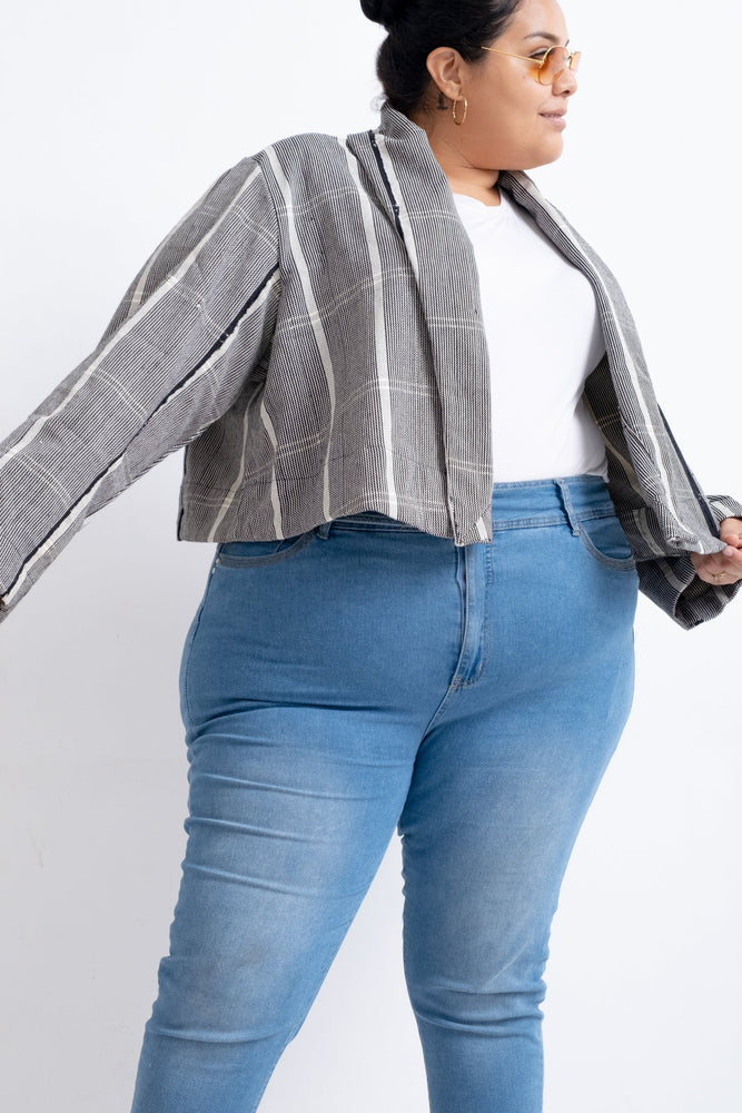 A woman wearing blue jeans and sunglasses while rocking the Abiba Jacket in Guinea Fowl.