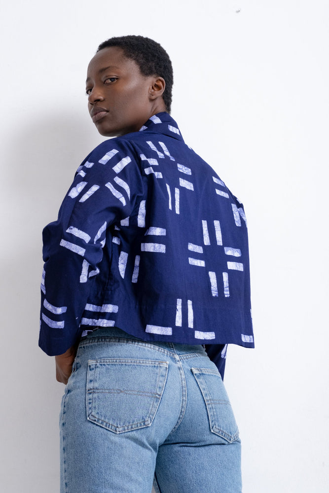 Back view of the Abiba Jacket in Middle Path, a dark blue with white patterned detail, paired with light blue jeans.