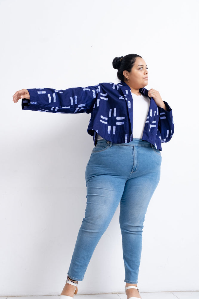 Dynamic Abiba Jacket in blue with white patterns, paired with a white top and jeans, captured in mid-motion.