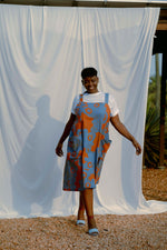 Amplo Dress silhouette against white backdrop, abstract blue-orange pattern, with side plants adding natural vibe.
