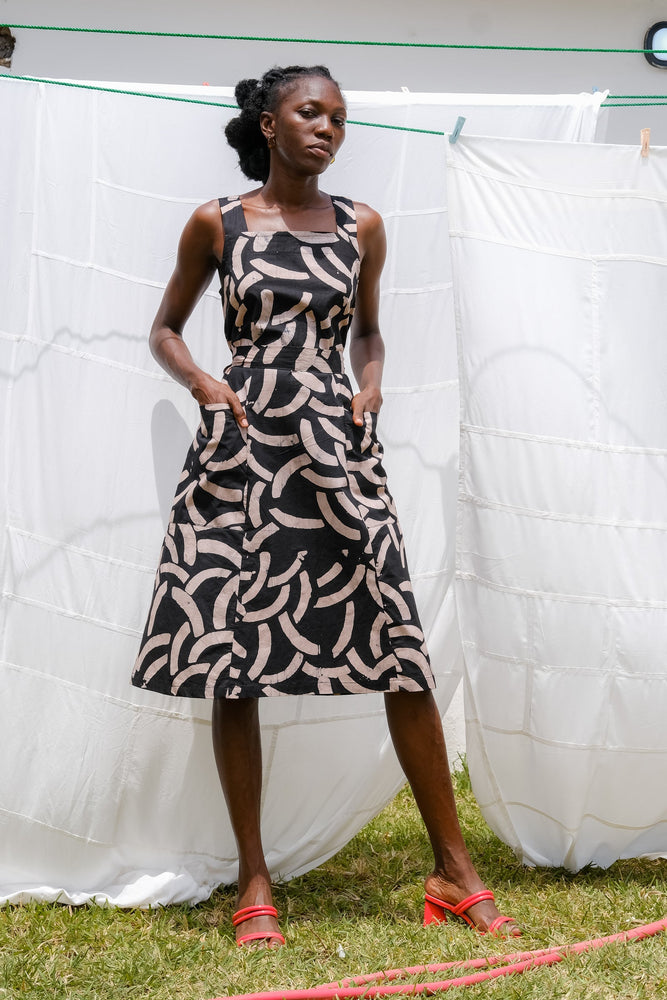 Amplo Dress in sleeveless style, adorned with black & beige pattern, paired with red shoes against a natural setting.