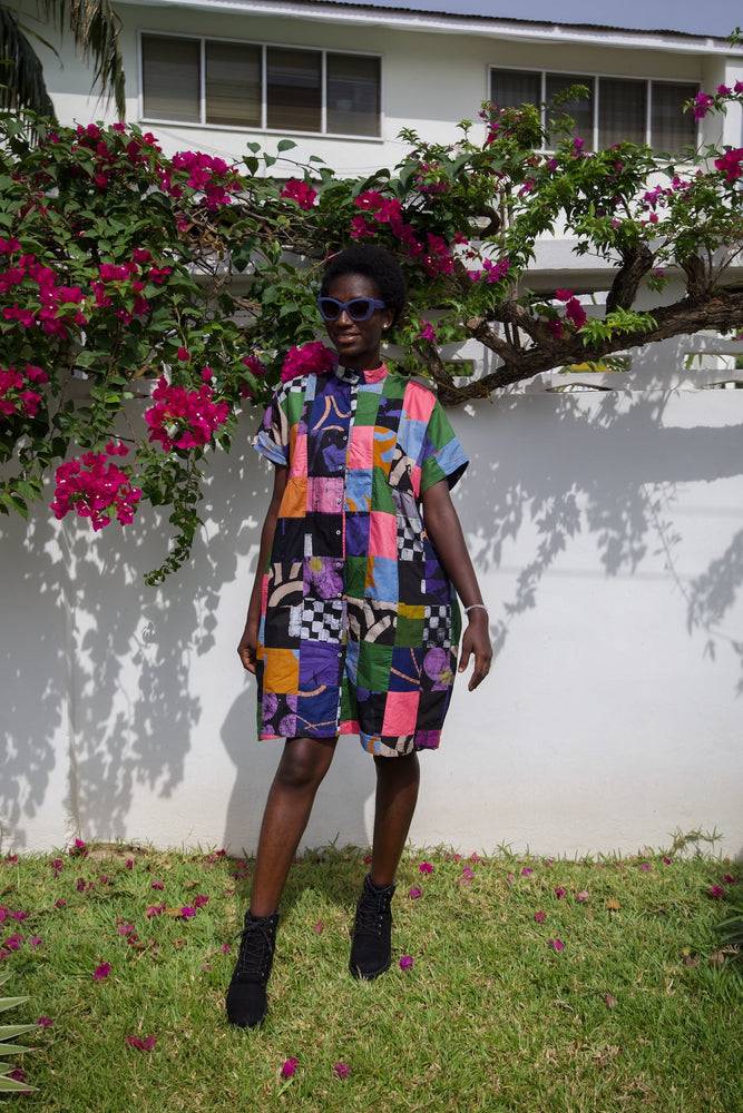 Colorful Bata Dress in Motley with Mandarin Collar and Back Cinch Tie, amidst a vibrant garden setting.