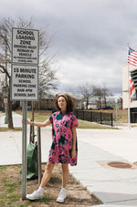 Person in the Bata Dress in Pool Party print, white sneakers, standing by school zone sign, American flag in background.