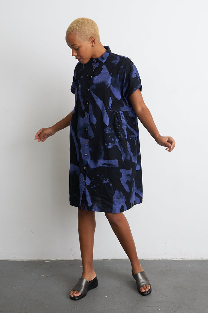 Chic Bata Dress with abstract blueish-purple print, short sleeves, and knee-length cut, against a white backdrop.