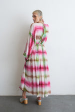 Serene Dreams Bata Dress with pink and green tie-dye, cinched waist, and grey clogs, against a white wall.