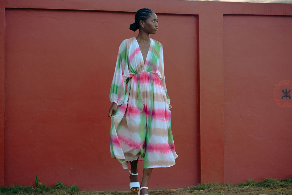 Elegant Bata Dress in vibrant tie-dye pattern with cinched waist and white sneakers, embodying a casual yet stylish essence.