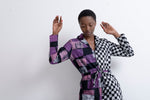 Vibrant Accra Jumpsuit in Adepa print, abstract purple and checkered patterns, expressive pose with hands up, white backdrop.