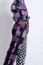Colorful Accra Jumpsuit in Adepa print, side view with hand on hip, showcasing patchwork design and tapered legs.