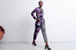Accra Jumpsuit in Adepa print, half purple-black stripes, half checkered, with pockets and belt, against white backdrop.