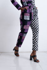 Fashion-forward Accra Jumpsuit in Adepa print, showcasing unique patchwork design with purple and checkered patterns.