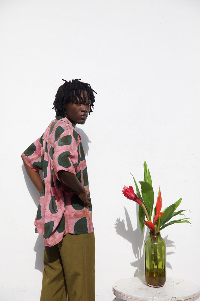 Person posing casually in a relaxed button up rayon shirt in a pink and dark green print.