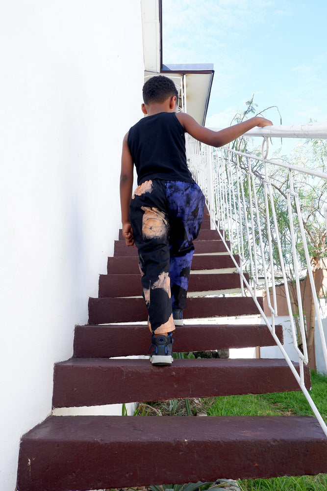 Active child in Kids Tendo Pants climbing stairs, showcasing durability and comfort, perfect for exploration.