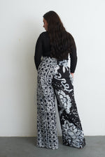 Latus Trousers in 2 Party System print, back view against a white wall, showcasing the contrasting prints.