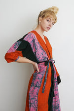 Vibrant Letsa wrap dress in colorful print, tied waist, model has hair in a bun, posed against a plain white background.
