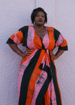 Colorful Letsa wrap dress in Carmine print, short wide sleeves, waist tie, accessorized with bracelets and necklace.