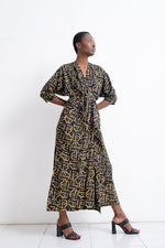 Stylish Letsa dress with golden print, short sleeves, and waist tie, paired with black heels on a white background.