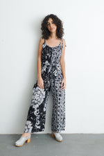Model in Ligo Jumpsuit with contrasting patterns, sleeveless design, and tie waist, against a plain backdrop.
