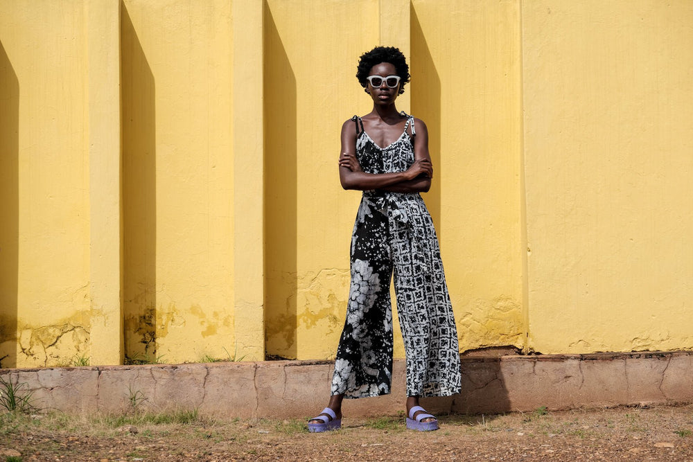 Model stands with arms crossed in the Ligo Jumpsuit in vibrant black and white pattern, a casual yet stylish look.