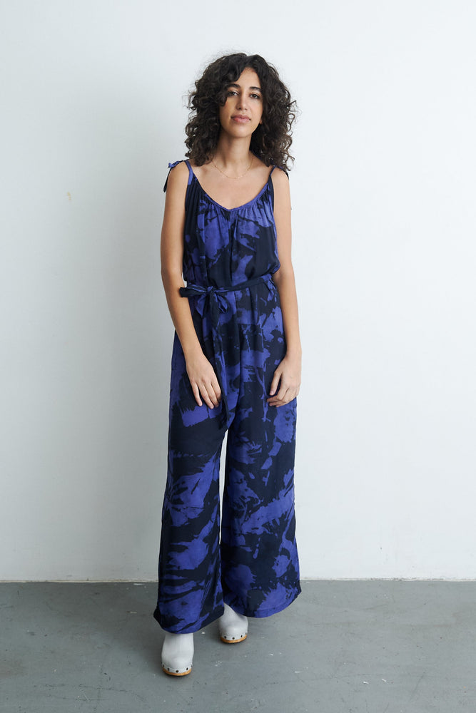 Ligo Jumpsuit in Rorschach print, model against light wall, showcasing the tie waist and lightweight fabric for summer style.