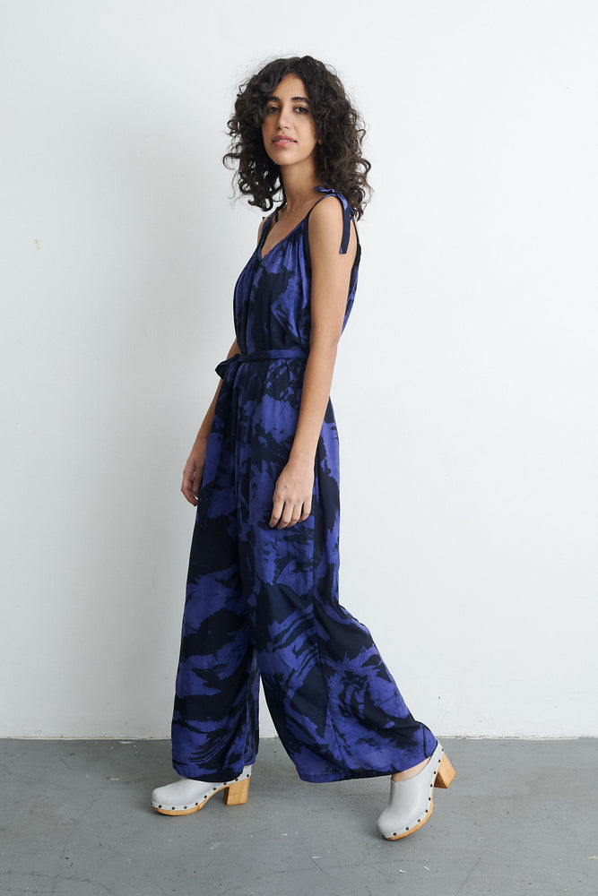 Ligo Jumpsuit in Rorschach print, model against light wall, accentuating the hand-dyed batik design and breezy silhouette.