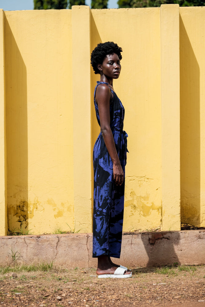 Ligo Jumpsuit in Rorschach print, model poses against a yellow wall, highlighting the jumpsuit’s airy rayon fabric.