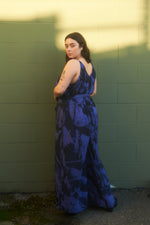 Side view of the Ligo Jumpsuit in Rorschach print, model poses against a green wall, giving an airy, flowy feel.