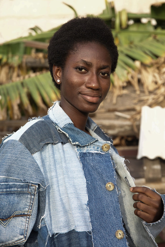 A close up of  a woman in denim jacket. Sustainable style, locally sourced, limited edition patchwork from Kantamanto, Accra.