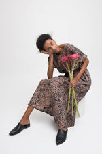 Nonna Dress in warm Snakebite print, loose silhouette with A-line hem and wide sleeves, accessorized with black shoes.