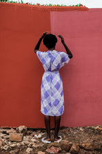 Model in Sampa Dress against dual-tone wall, highlighting the dress’s purple and white print and effortless style.
