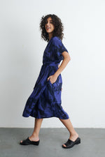Stylish Sampa Dress in batik design, tea-length with dolman sleeves and wrap front, handcrafted in Ghana.