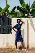 Sampa Dress in Rorschach print, tea-length with dolman sleeves, tied at waist, batik pattern, outdoor setting.