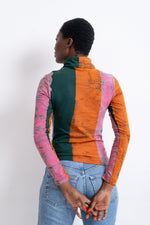 Back view of Stricta Turtleneck in Carmine print, multicolored stripes, blue jeans, hands clasped behind.