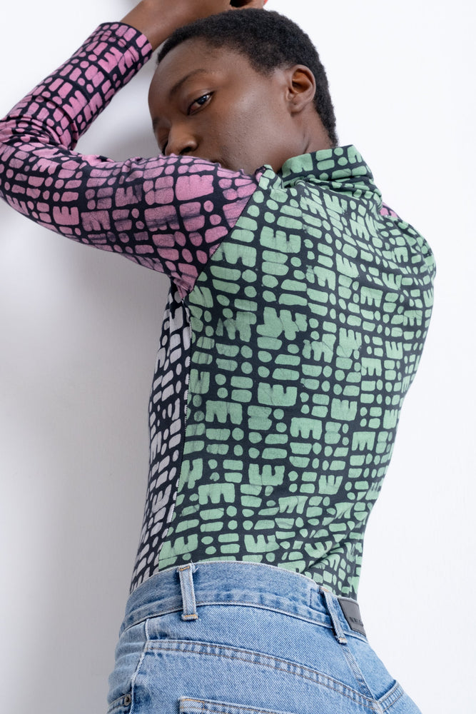 Back view of Stricta Turtleneck with green and black pixel-like pattern, paired with denim, handcrafted in Ghana.