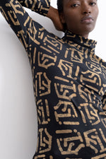 Side view of a long-sleeved shirt with beige symbols on black, capturing movement and intricate design details.