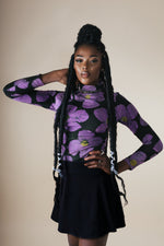Model in a stylish outfit featuring the Stricta Turtleneck in Love Perfect a floral print, paired with a black skirt.