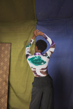 Back view of Osei-Duro turtleneck in green and white batik design, handcrafted in Ghana, paired with dark trousers.
