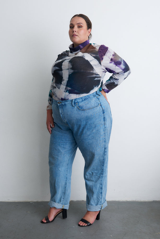 Person in Osei-Duro tie-dye top and jeans, showcasing the vibrant hand-dyed pattern, ideal for casual wear.