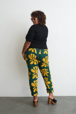 High-waist Vitta Trousers with unique green-yellow batik design, snug fit, and invisible side zipper, made in Ghana.