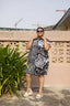 A woman wearing an oversized cotton dressed in size 2X outside. The dress has a black and white batik pattern.