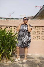 A woman wearing an oversized cotton dressed in size 2X outside. The dress has a black and white batik pattern.