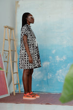 Side view of a woman wearing an oversized cotton dress in size small with a black and white grid pattern.