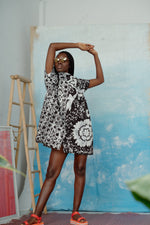 Front view of an oversized cotton dress in size small with a black and white abstract flower and grid pattern.