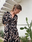 Stylish woman in a black and white Letsa dress with batwing sleeves, standing gracefully next to a cactus.